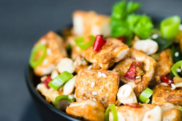 Kızarmış tofu, kaju, chili koyu arka plan üzerine ilave edin. Yakın çekim
