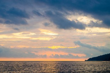 Gün batımında karanlık ve dramatik bir gökyüzü. Çakıl taşı deniz plajı