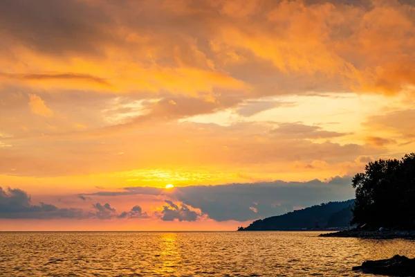 Dramatická oranžová obloha při západu slunce. Mraky. Ostrov v moři — Stock fotografie