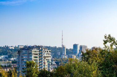Tepedeki uzun apartmanlar. Güzel modern mimari. Televizyon kulesi. Yeşil bitki örtüsü. Mavi gökyüzü. Havadan. Sıcak bir şehir konsepti