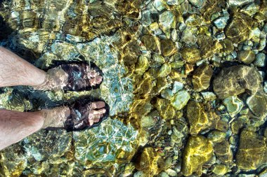 Ayak bileklerinde yüksek terlikler plajdaki açık deniz suyunda.