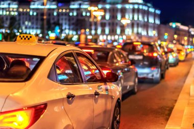 Trafik sıkışıklığı içindeki taksi gece şehrin ışıklarında ve bokeh