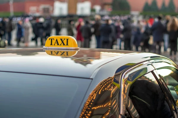 En taxi parkerad på trottoaren av en stor gata med stora trafikstockningar, återspeglar bilen ljuset i nattstaden — Stockfoto