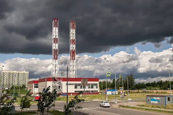 Plant with chimneys and thick white smoke smoking against on the of black thunderclouds background — Stock Photo, Image