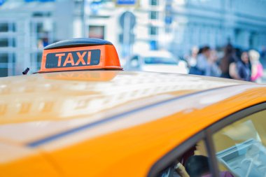 Büyük bir şehrin merkezinde sarı bir arabanın çatısında dama taksisi.