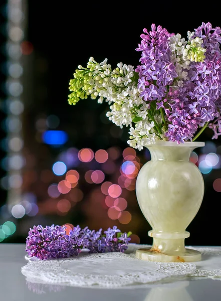 Oniks vazodaki leylak çiçekleri şehrin arka planında ve bokeh