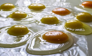 Çiğ ve taze yumurtalar beyaz arka planda parıldıyor.