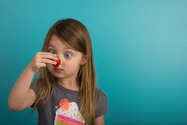 Little girl looking at a strawberry — Stock Photo, Image