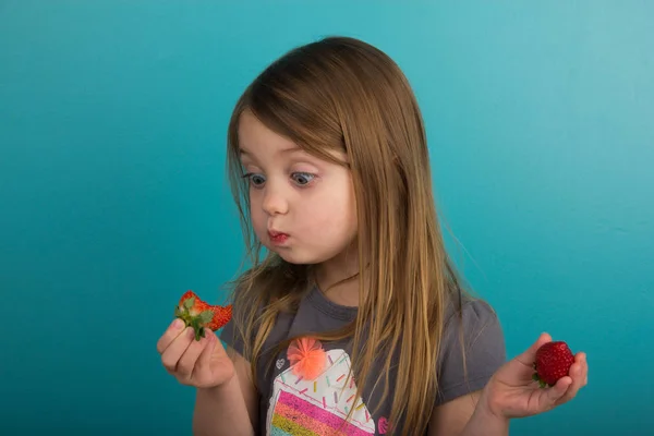 Little girl tasting a strawberry — Stock Photo, Image