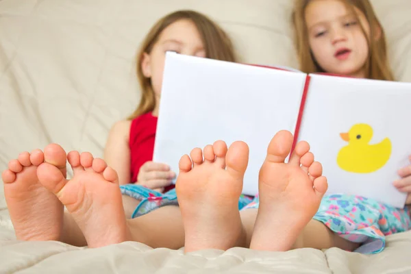Barn läser en bok i sängen Stockbild