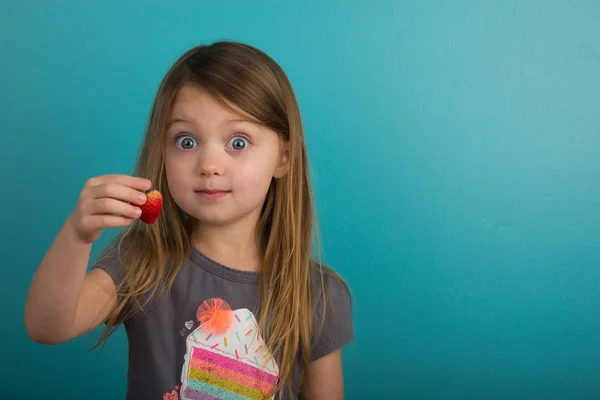 Niña mostrando una fresa Imágenes De Stock Sin Royalties Gratis