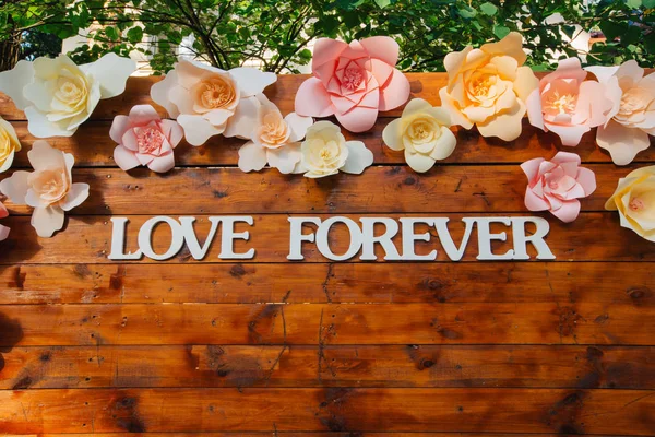 รักสัญลักษณ์ตลอดไปบนกระดานไม้ที่ตกแต่งด้วยดอกไม้ — ภาพถ่ายสต็อก