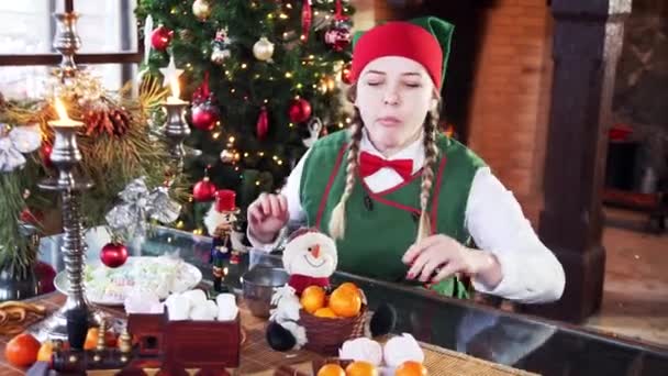 Dziewczyna Kostiumie Elfa Siedzi Przy Świątecznym Stole Zabawny Elf Bierze — Wideo stockowe