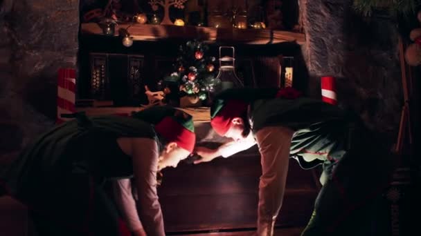 暗い部屋のクリスマスエルフは明るい胸から古い本を取ります — ストック動画