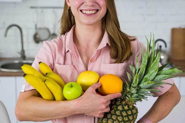Nuori hymyilevä tyttö pitää käsissään trooppisia hedelmiä. . — kuvapankkivalokuva