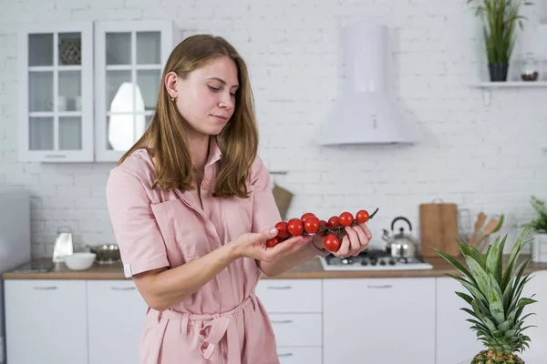 Haara kypsä kirsikka tomaatti käsissä nuori tyttö valkoisessa keittiössä . — kuvapankkivalokuva