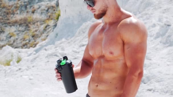 Uomo Nudo Forte Apre Una Bottiglia Nera Beve Acqua Fitness — Video Stock