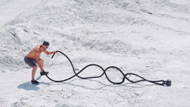 Athletic strong man doing exercises with ropes outdoors on the sand. Shirtless bodybuilder training. — Stock Footage Athletic Strong Man Doing Exercises Ropes Outdoors Sand Shirtless Bodybuilder Stock Footage