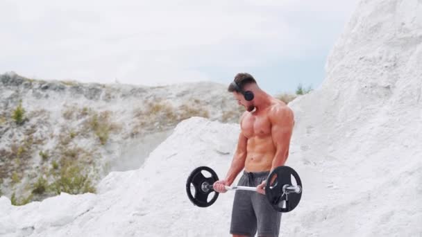 Athletic Man Naked Torso Headphones Does Exercises Biceps Barbell Fitness — Stockvideo
