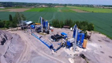 Asfalt üretimi. Tarladaki fabrikanın bölgesinde yüksek metal variller ve yapılar var..