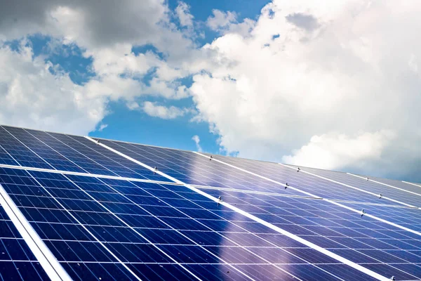 Evin çatısında bulutlu mavi gökyüzüne karşı güneş panelleri inşa etmek. Yenilenebilir enerji
