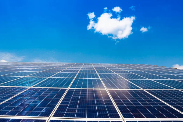 Beyaz bulutlu mavi gökyüzüne karşı elektrik üretmek için güneş panelleri. Alternatif enerji
