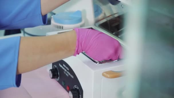 一个戴手套的美容师从温度灭菌器中取出工具 — 图库视频影像