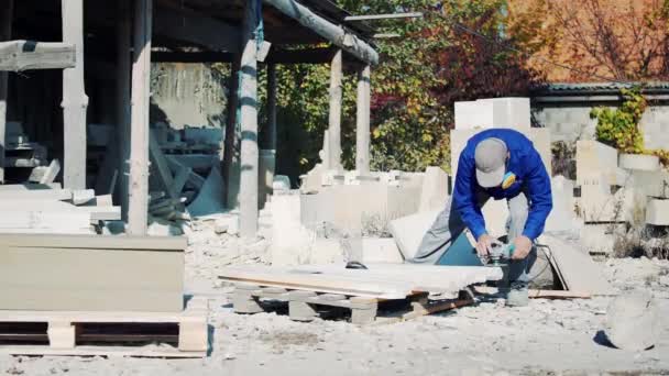 呼吸器の男が電気角度グラインダーで石を研磨します 砂岩の芸術加工工場 — ストック動画