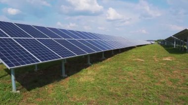 Yeşil çimenli bir alanda güneş enerjisi santralinin sıralı panelleri..