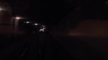 Beton kolonları olan karanlık bir metro tünelinde metro vagonu..
