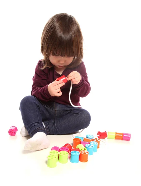 Niña de dos años jugando con carretes de algodón — Foto de Stock