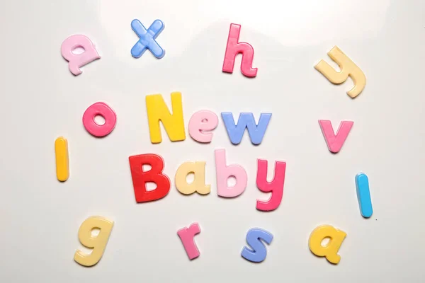 Novo bebê soletrado em letras ímã — Fotografia de Stock