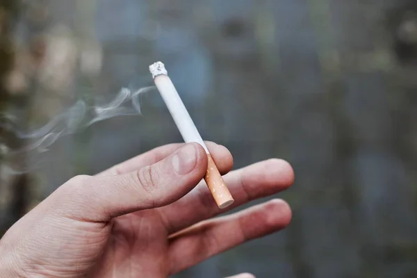 Сигарета в руке мужчины — стоковое фото