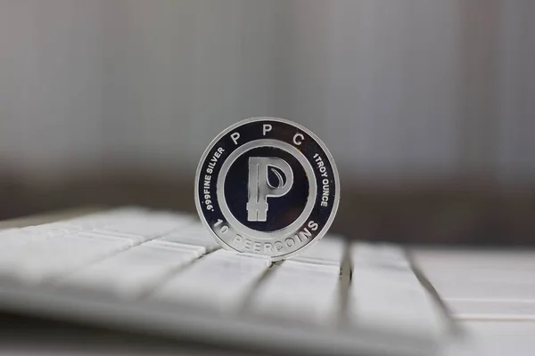 Digital currency physical metal silver peercoin on the white computer keyboard.