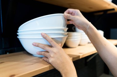 El ahşap raf üzerinde beyaz bir büyük kase aldı