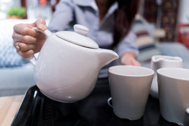 Çay beyaz seramik sürahi bir cam içine dökülür.