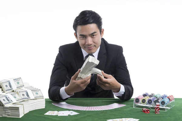 O homem bonito segurando pilhas de dólares na mão na mesa do casino — Fotografia de Stock