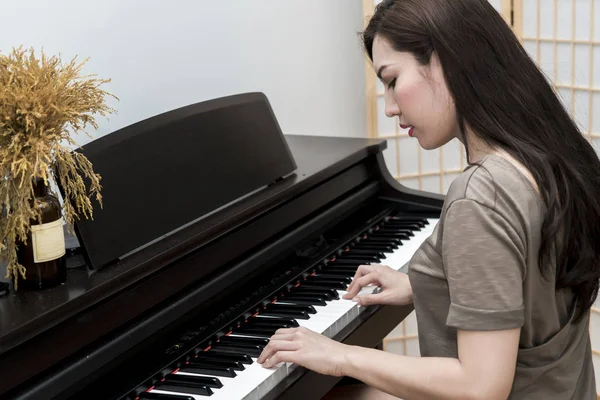 年轻的音乐家女人弹钢琴在客厅里 — 图库照片