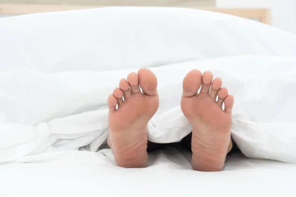 Menselijke voet onder bed vel — Stockfoto