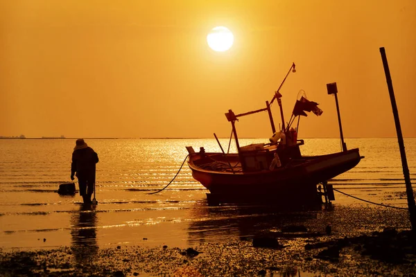 Silhouette dell'uomo e barca da pesca in legno sulla spiaggia di sabbia — Foto Stock