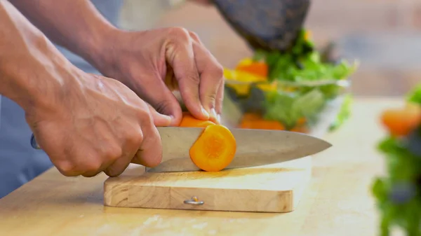 De cerca la mano del hombre está cortando la zanahoria en el bo de cristal — Foto de Stock