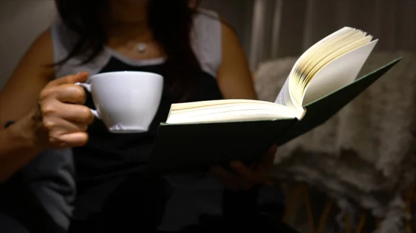 Mujer sosteniendo café mientras lee un libro —  Fotos de Stock