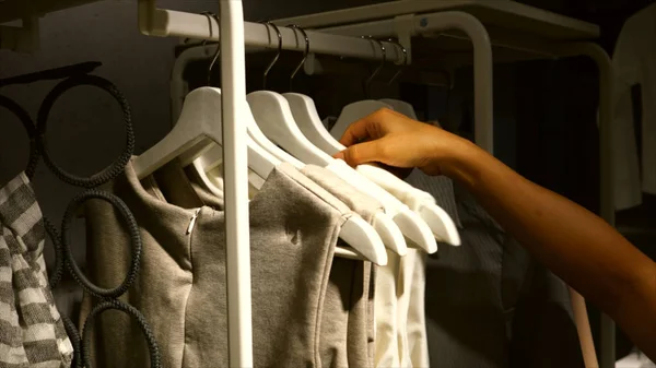 Mujer eligiendo vestido en un estante — Foto de Stock