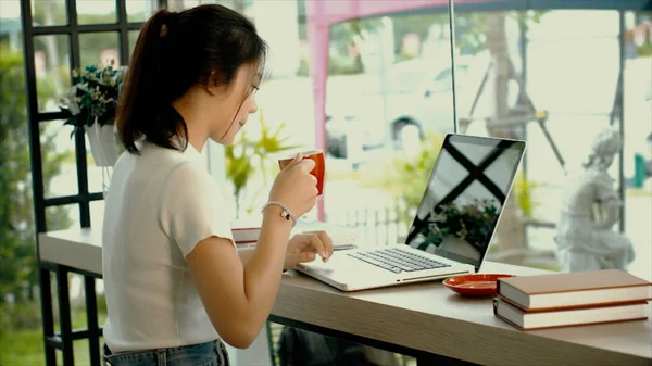 Menina adolescente asiática bonita está trabalhando em um laptop — Fotografia de Stock