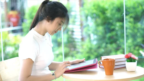 Sidovy av asiatiska teenage maskinskrivning på tablett i trädgården — Stockfoto