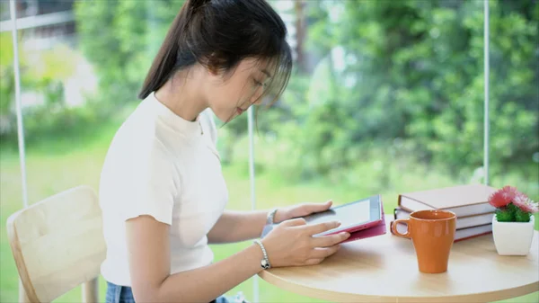 Vista lateral da adolescente asiática digitando no tablet no jardim — Fotografia de Stock