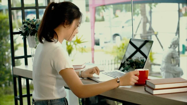 Menina adolescente asiática bonita está trabalhando em um laptop — Fotografia de Stock