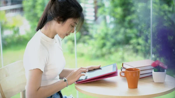 Side view of Asian teenage typing on tablet in garden — Stock Photo, Image