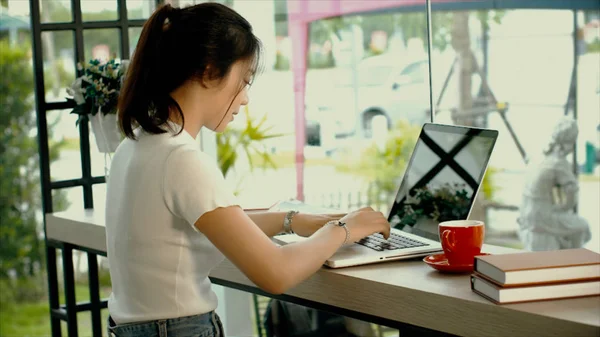 Menina adolescente asiática bonita está trabalhando em um laptop — Fotografia de Stock