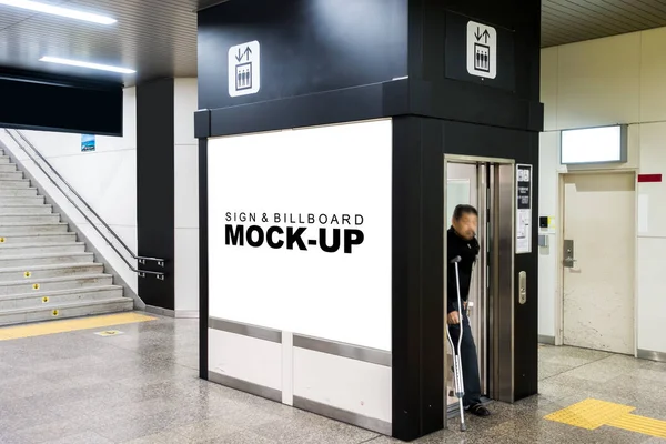 The mock up of horizontal rectangle billboard on the wall of elevator cabin at  train station area, blank white screen for advertisement with clipping path, Near the stairs and blurred man walk out with crutches